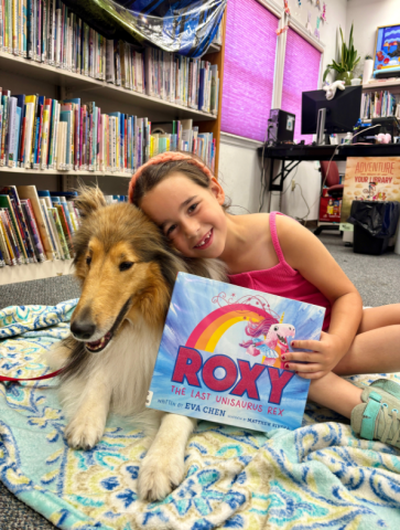 a girl and a collie dog posing with a book called Roxy.