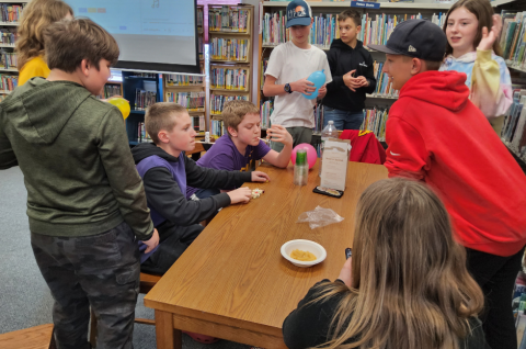 a group of teens around a table playing games