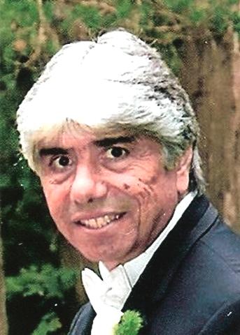 A photo of a grey haired man wearing a suit with trees in the background