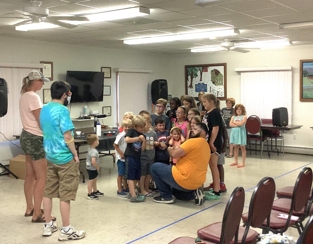 A group of children are being guided in a science experiment while two adults look on